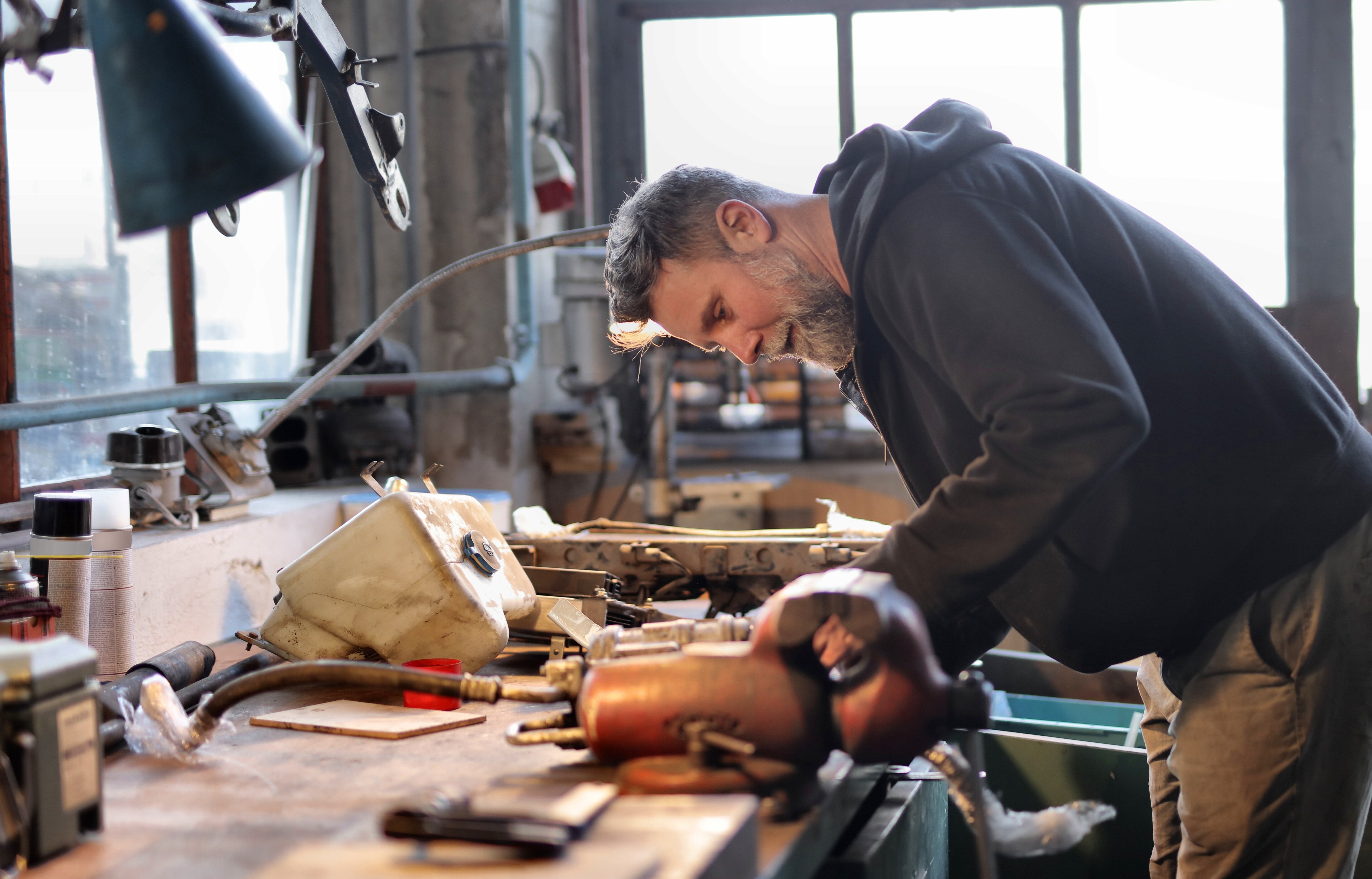 Smiling male mechanic repairing details in garage